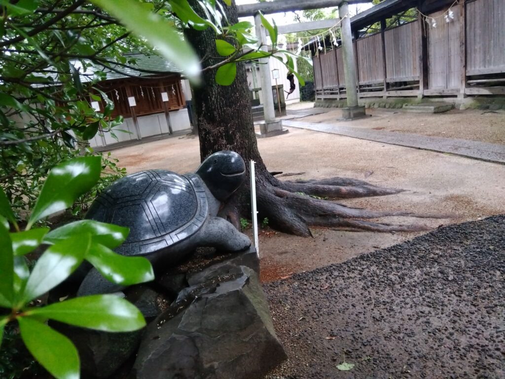 A serene corner of a Japanese shrine, featuring a large turtle statue, symbolizing longevity and spiritual protection.