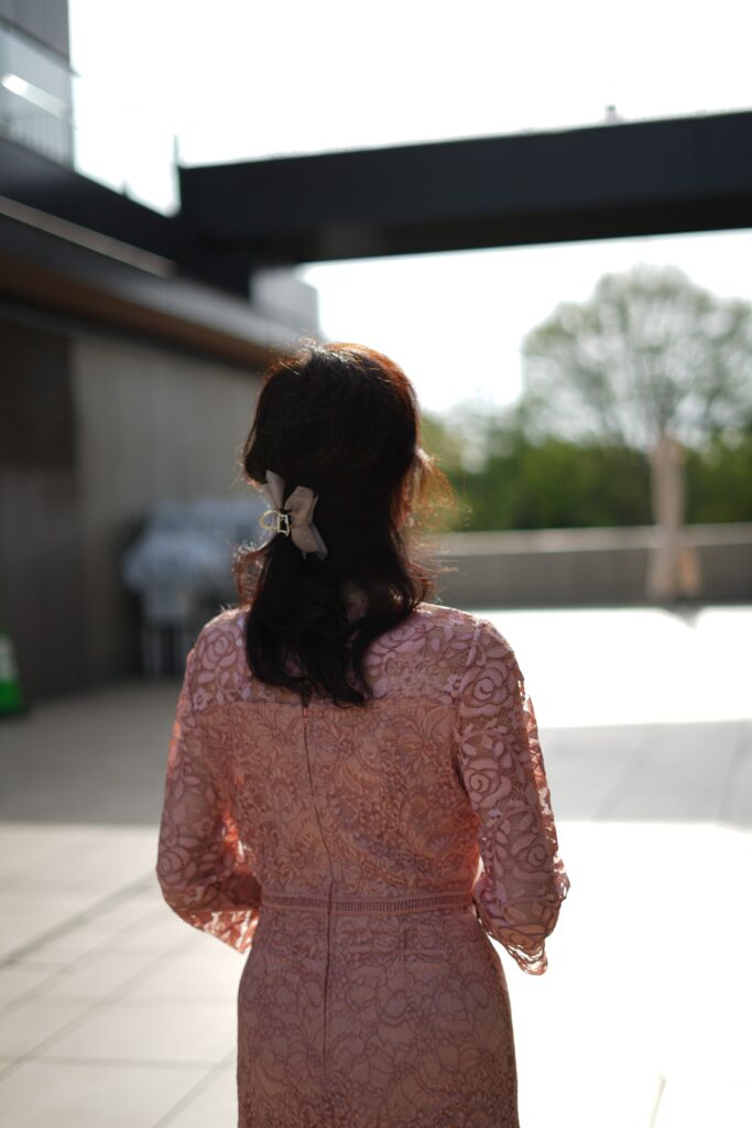 ピンクのドレスを着た女性が青空の下に立つ後ろ姿