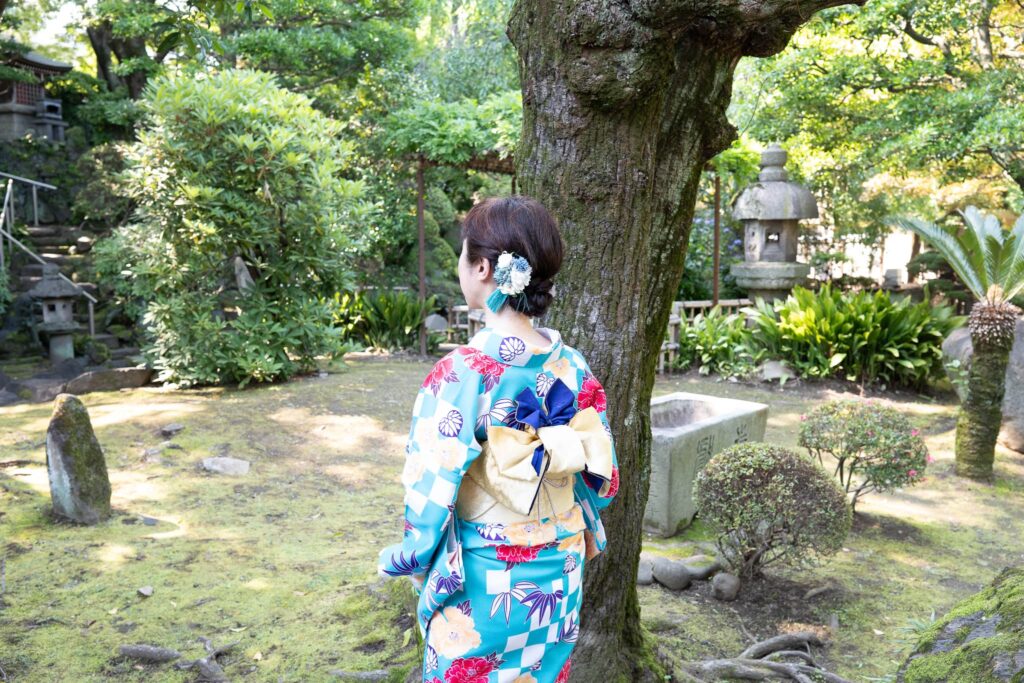 青い着物を纏った著者の後ろ姿、声の記憶と祈りの道を歩んできた証