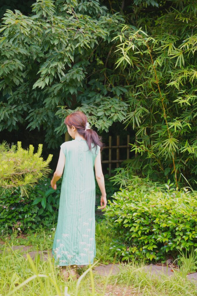 山葵色の竹模様のノースリーブ着物ドレスを着たモデルの後ろ姿、初夏の日本庭園で立つ