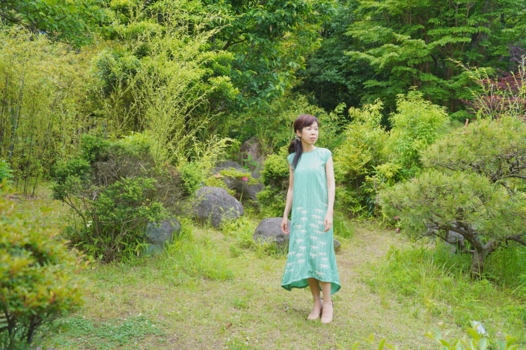山葵色の竹模様の着物ドレスを着て自然の中に佇むシンガーソングライター天貝観姫